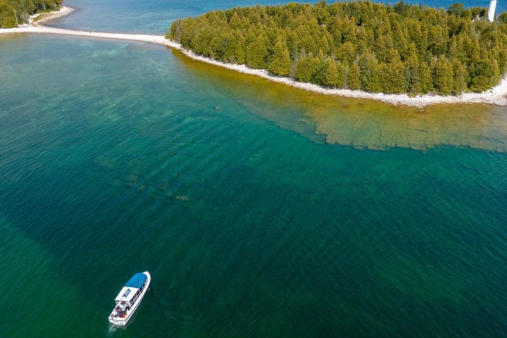 an arial view of scenic tour boat on lake michigan with cana island lighthouse