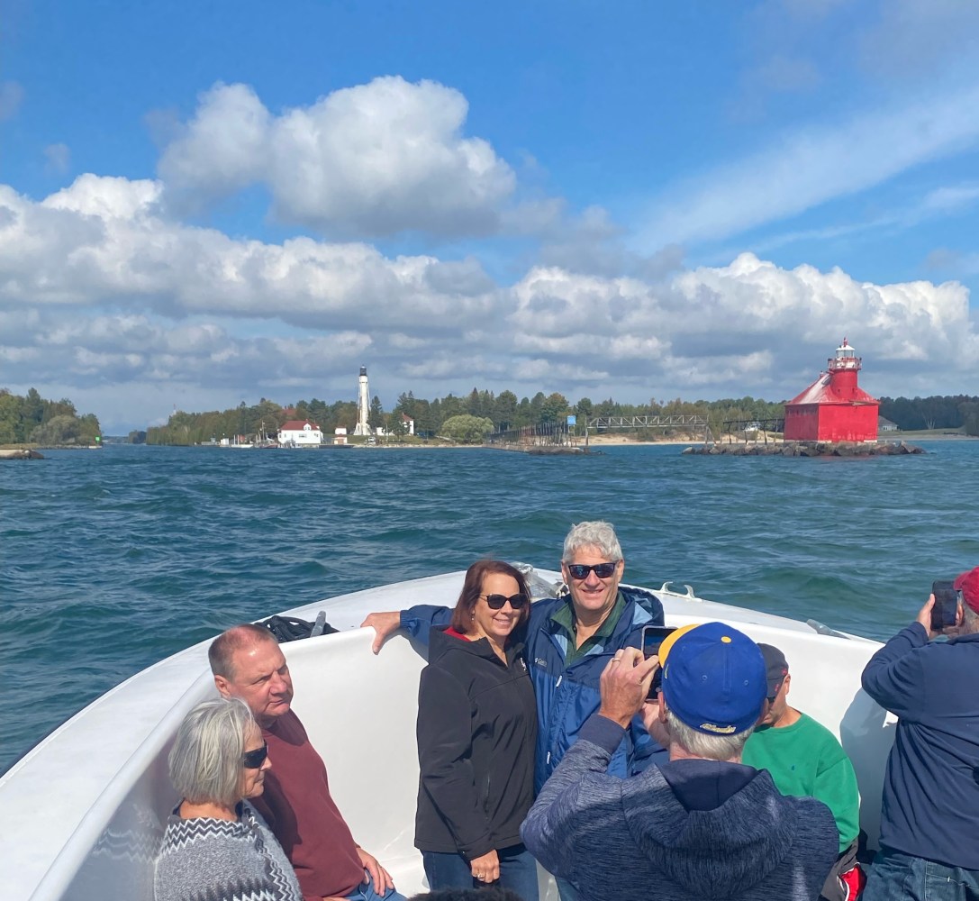 a group of people on a tour boat on lake michigan with lighthouses in the background
