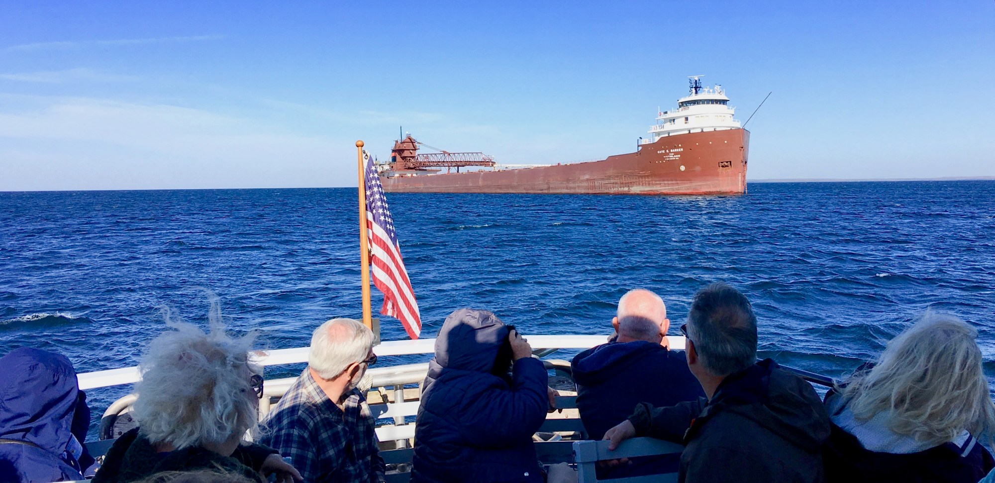 BP2 Guests freighter FEATURED a group of people in a tour boat on sturgeon bay looking at a large ship