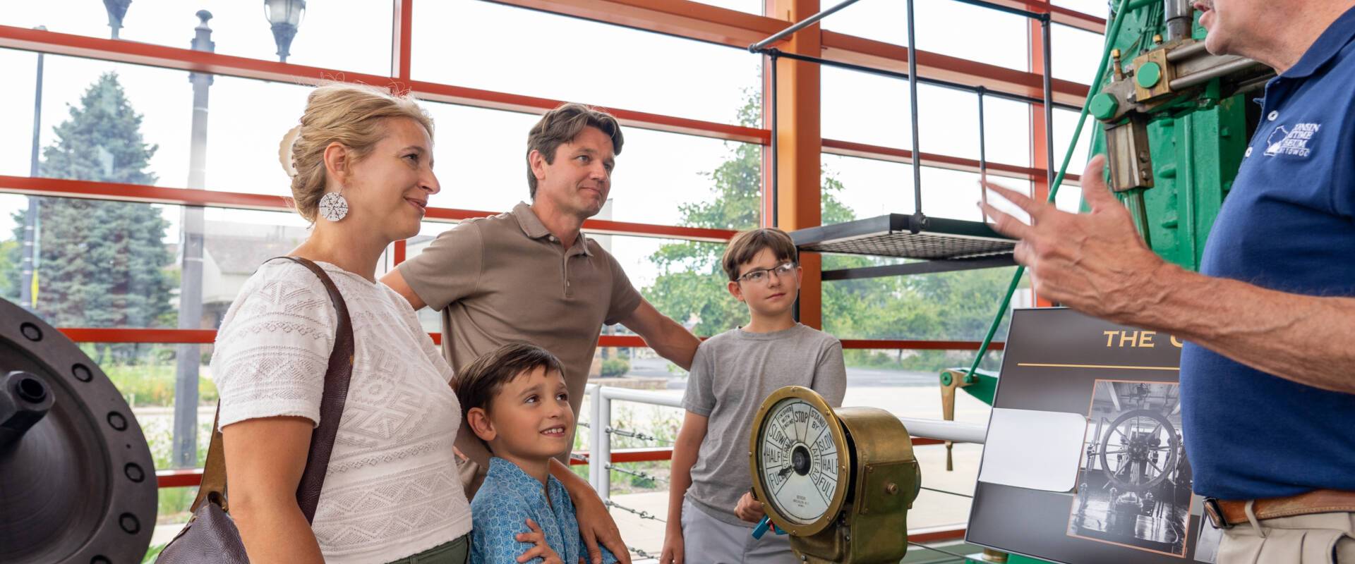 A family and a museum staff standing next to an exhibit at Wisconsin Maritime Museum