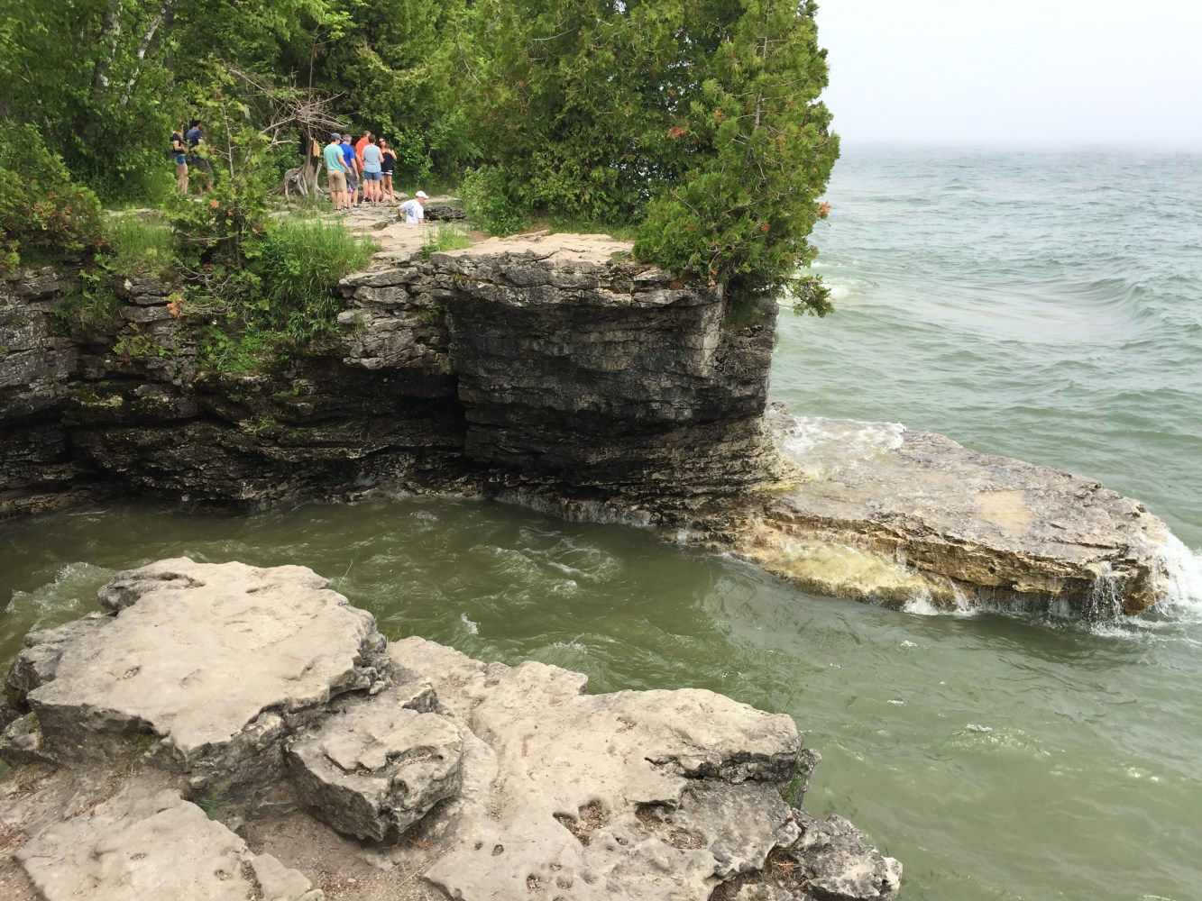 a group of people on a rock near a large body of water