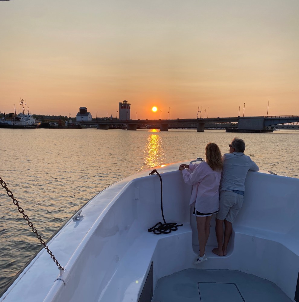 a couple in a boat on a body of water watching the sunset