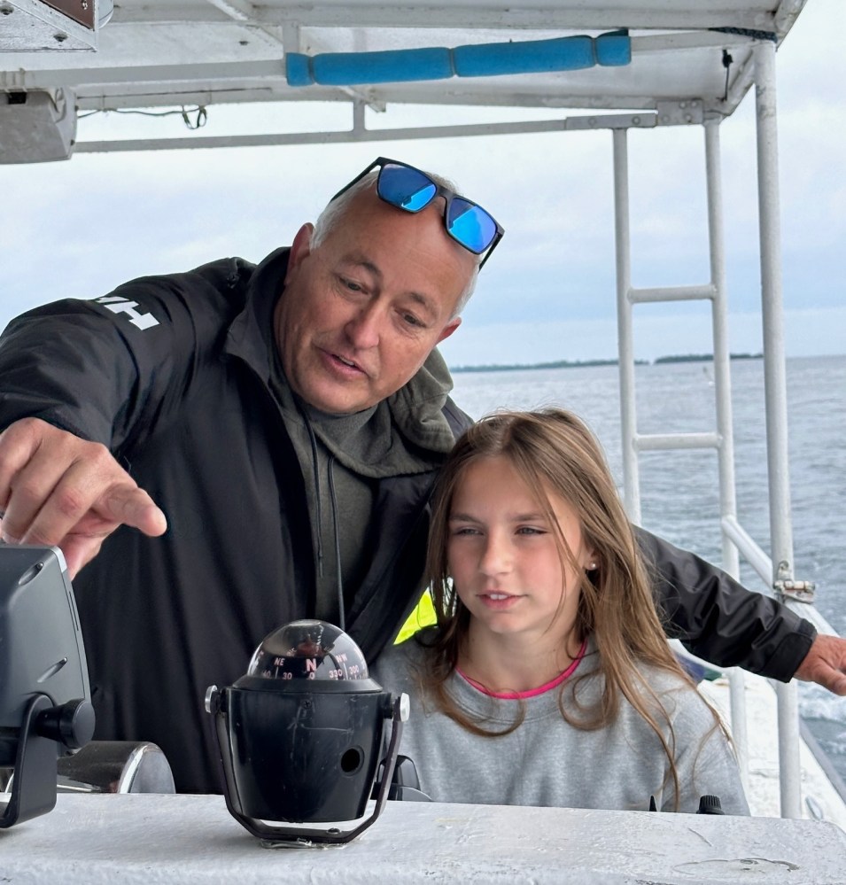Man and girl looking at a compass on a boat.