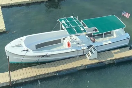 Boat with green canopy docked at pier, American flag at stern.